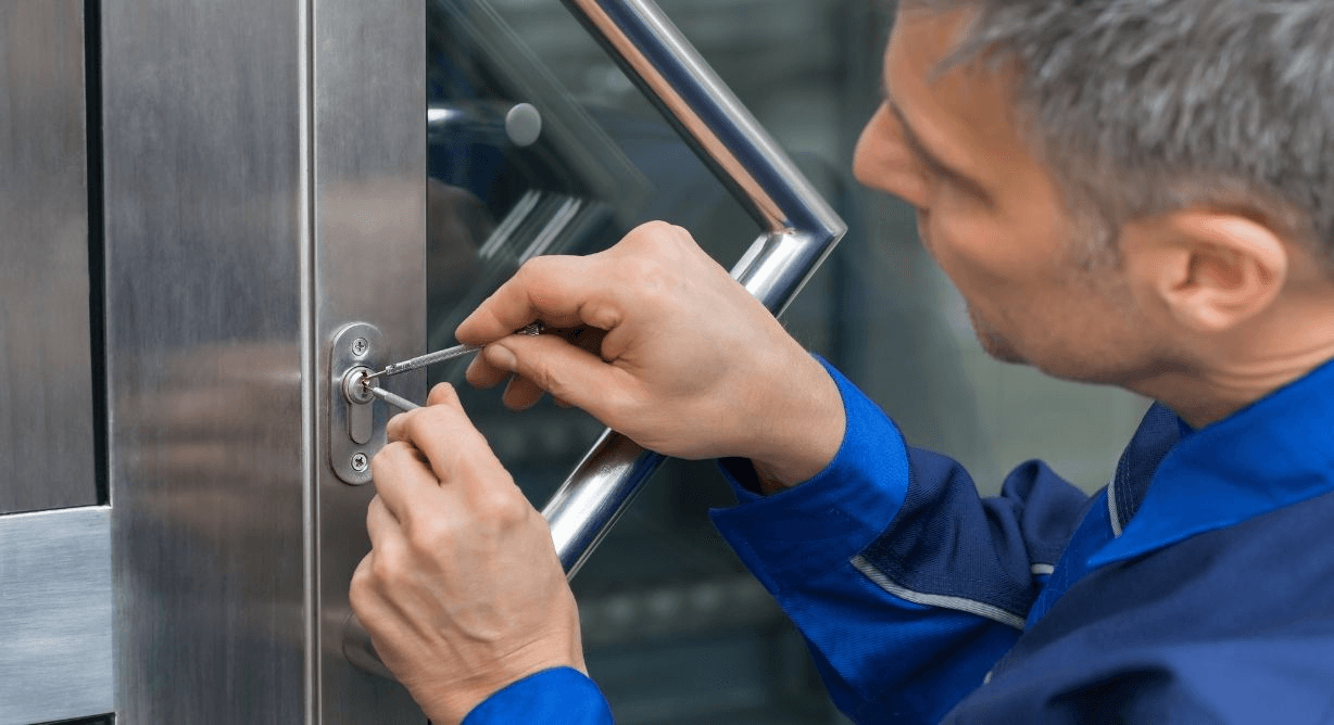 Serrurier homme en bleu de travail intervenant sur une serrure de porte