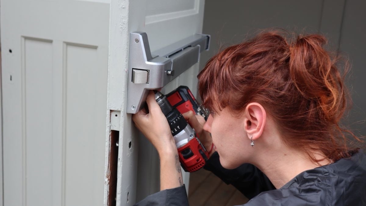 Pose d'une serrure sur une porte d'entrée à la visseuse, gros plan sur les mains au travail