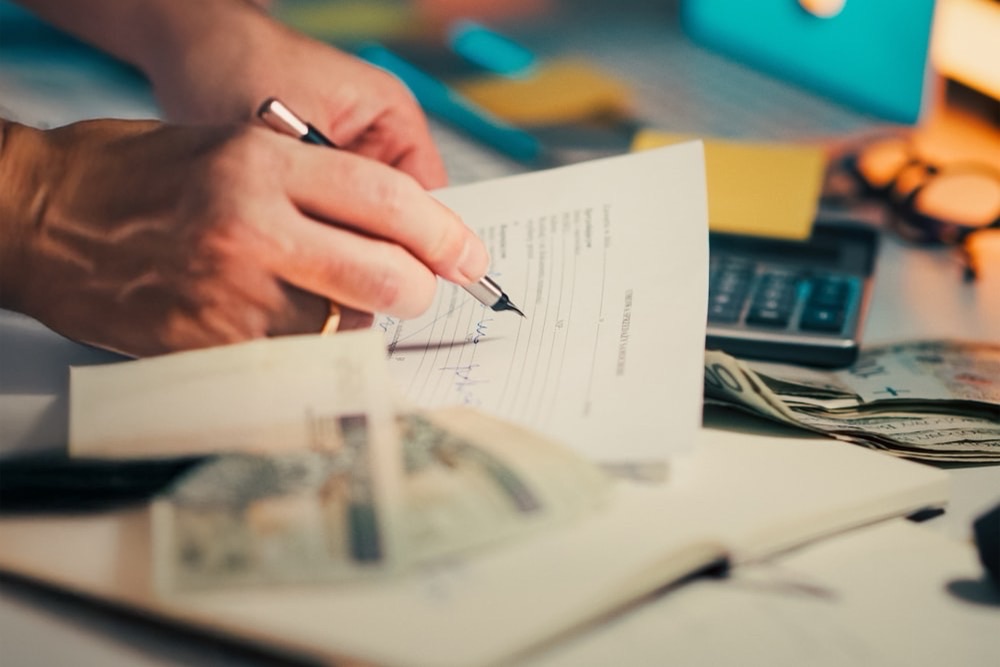 Main signant un devis papier détaillé avec stylo et calculatrice