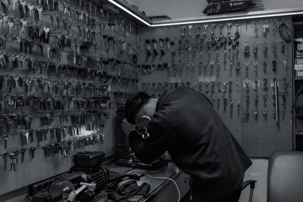 Serrurier au travail à son établi dans un atelier garni de clés