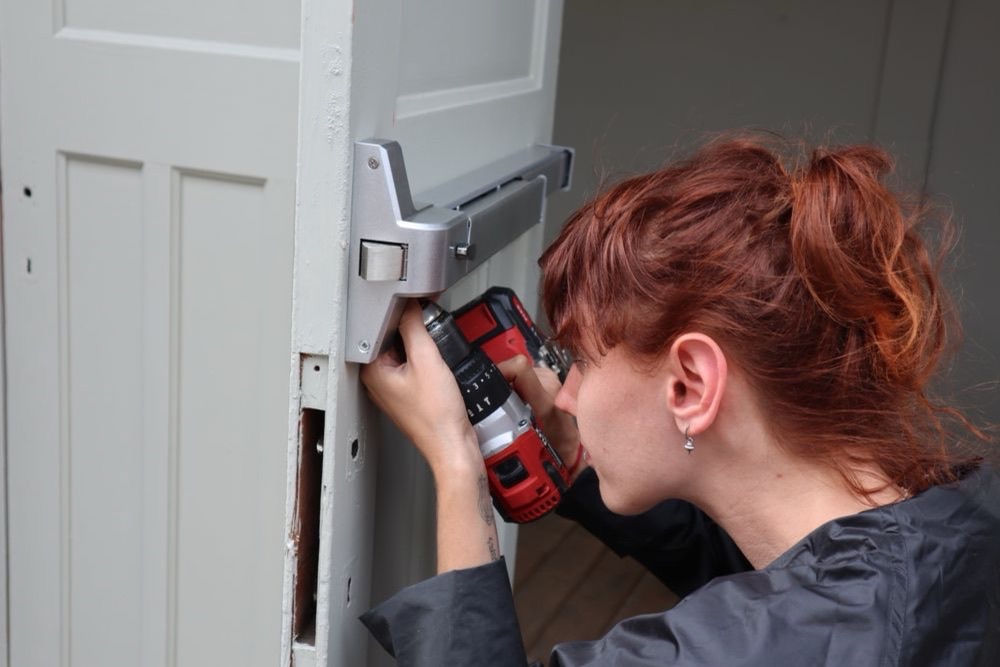Artisan intervenant sur la serrure d'une porte avec un outil