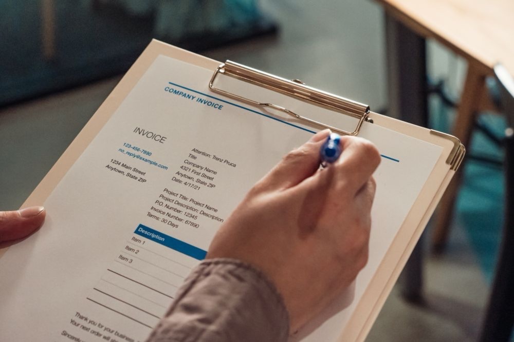 Main tenant un devis détaillé avec un stylo avant de valider une intervention